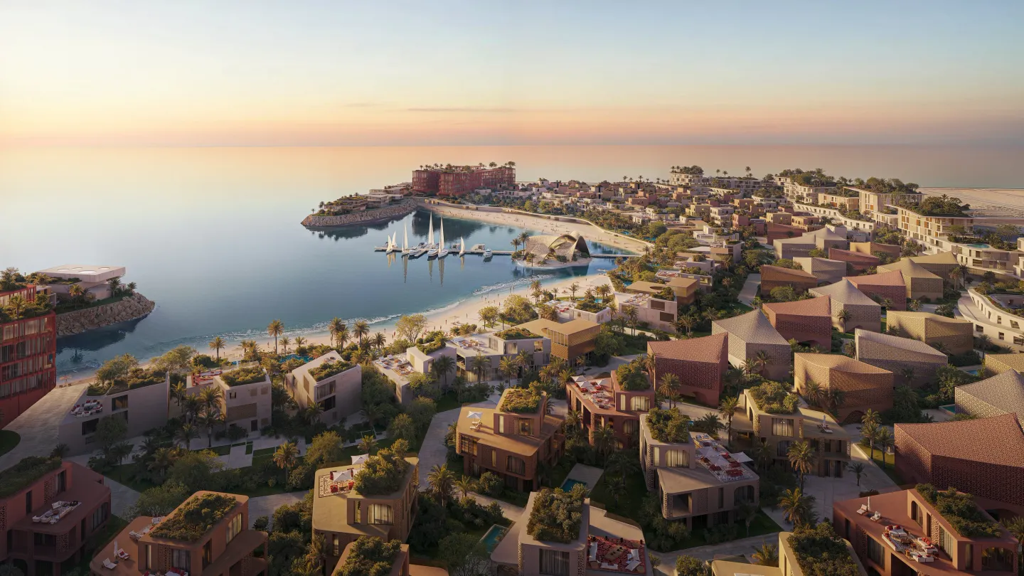 Mira Coral Bay from the air at dusk: villa clusters and apartment buildings around the bay, marina and beach clubs