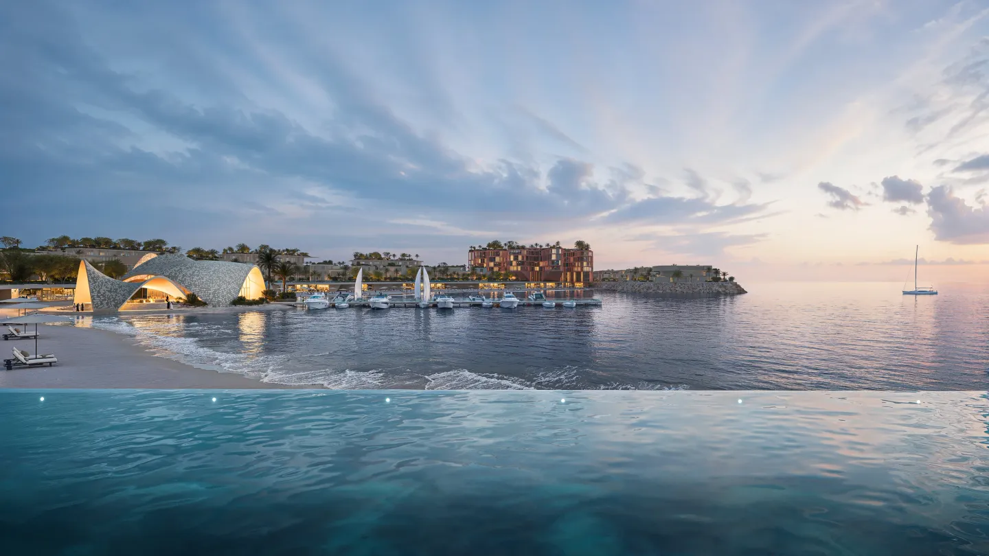 The Mira Coral Bay beach club pavilions lit at dusk beside the marina, seen across an infinity pool