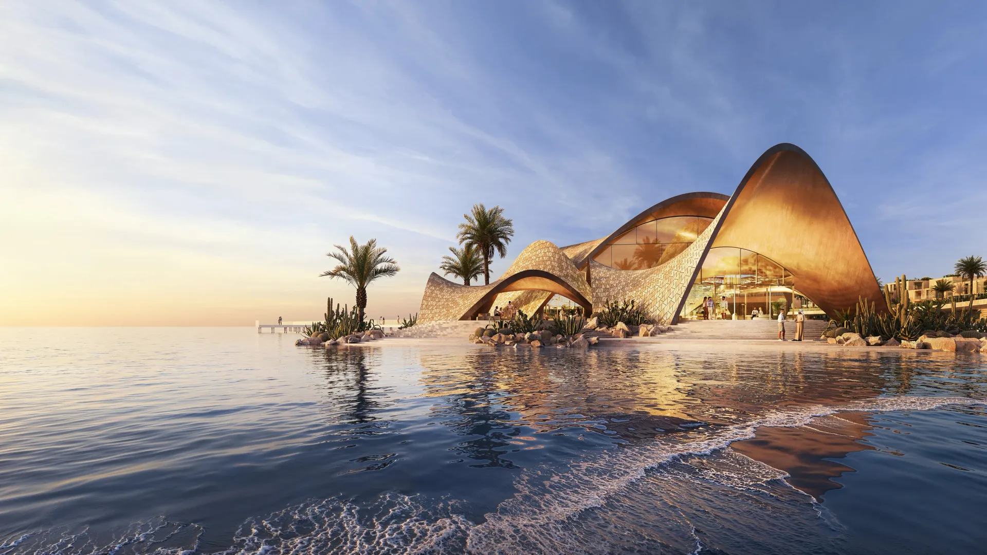 The shell-formed beach club pavilion at Mira Coral Bay at sunset, ringed by palms and the shoreline