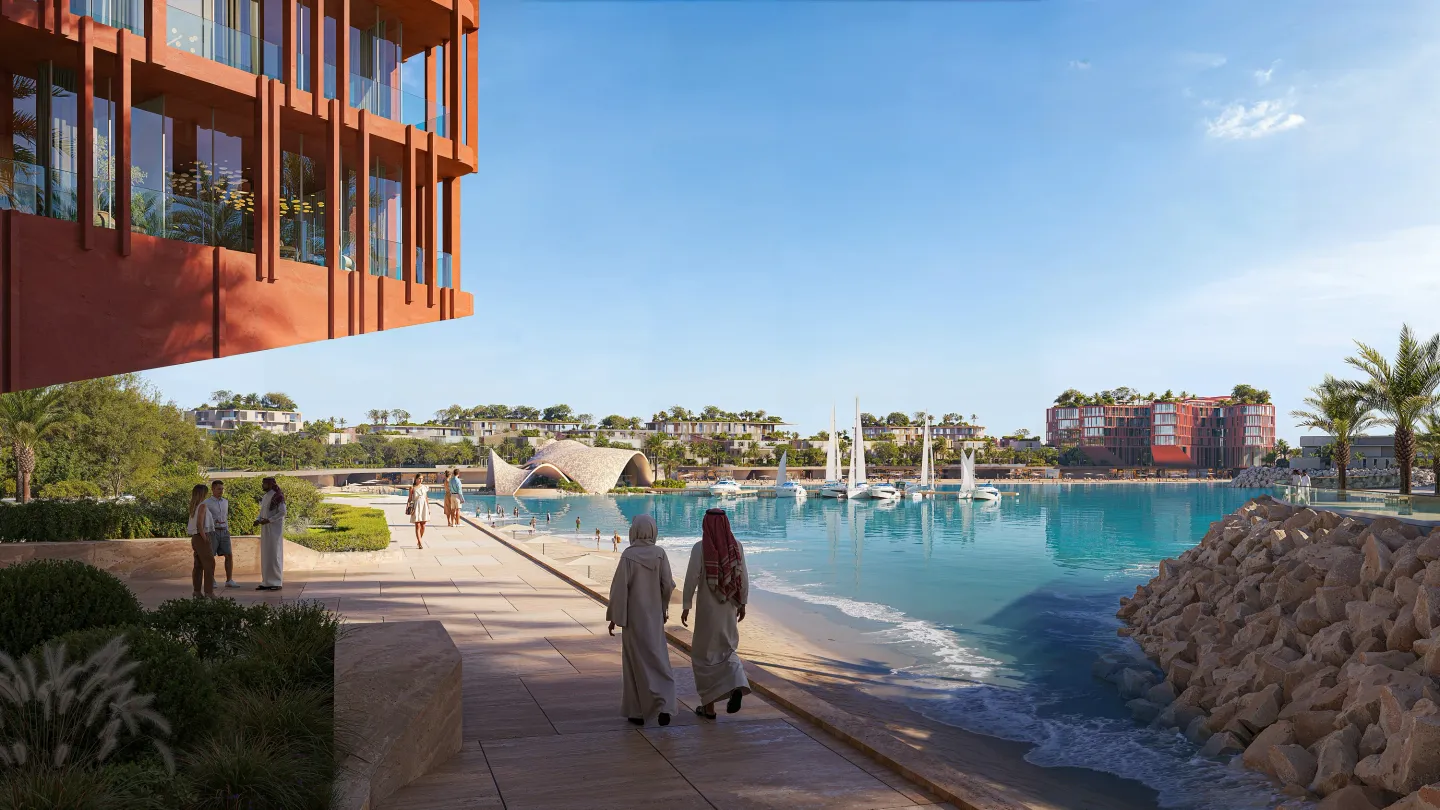 The Mira Coral Bay waterfront promenade, with residents walking towards the bay and sailboats on the water