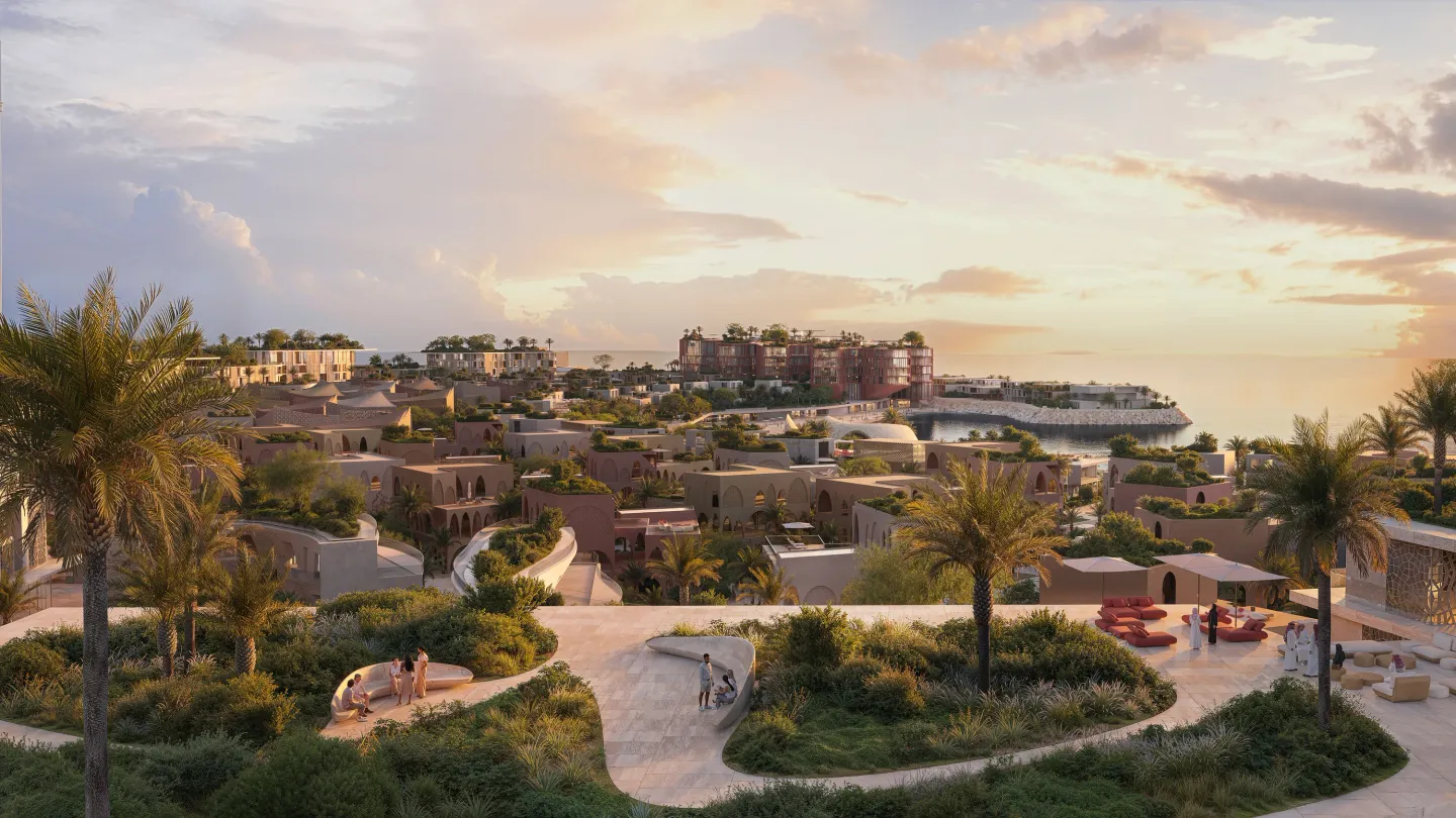 Green-roofed villa clusters at Mira Coral Bay at sunset, with the bay and hotel beyond
